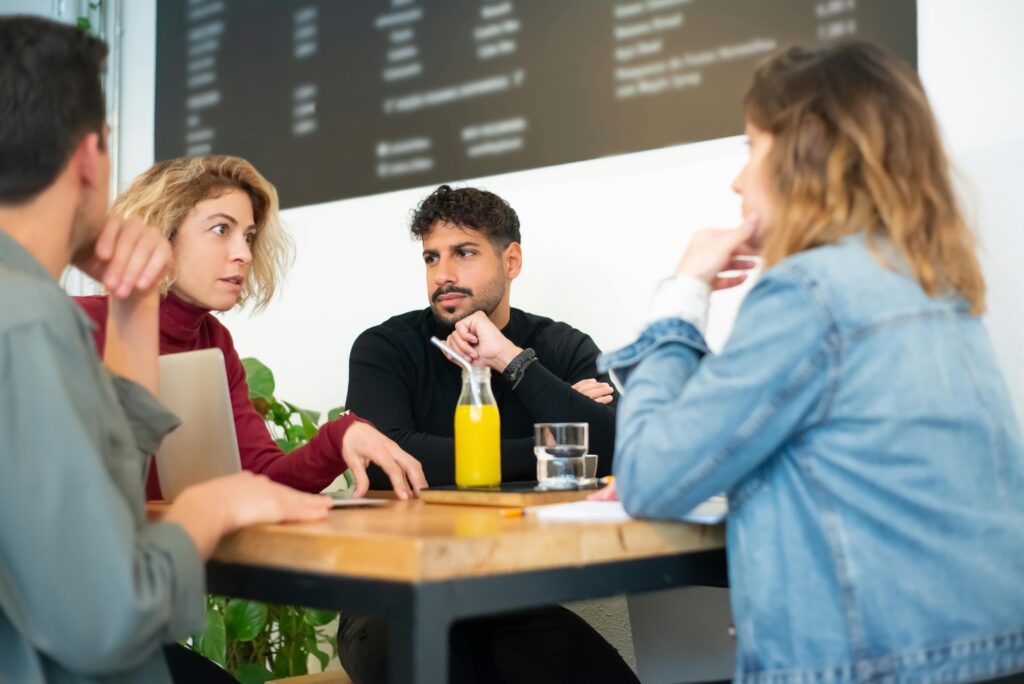 A group engaged in a thoughtful discussion at a trendy café in Portugal, fostering creativity.